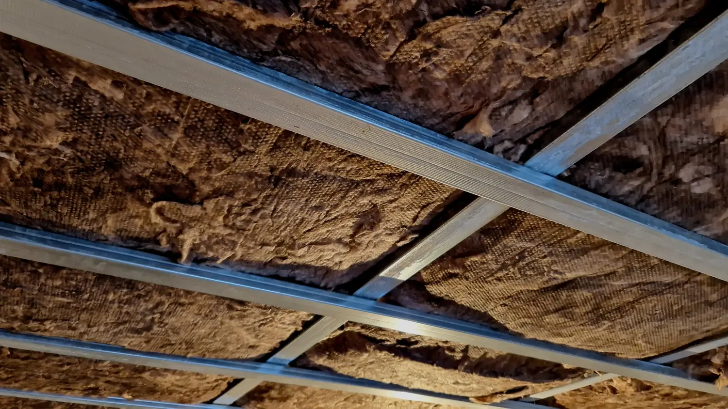 Mineral wool insulation installed between metal framing in a suspended ceiling system for improved thermal performance